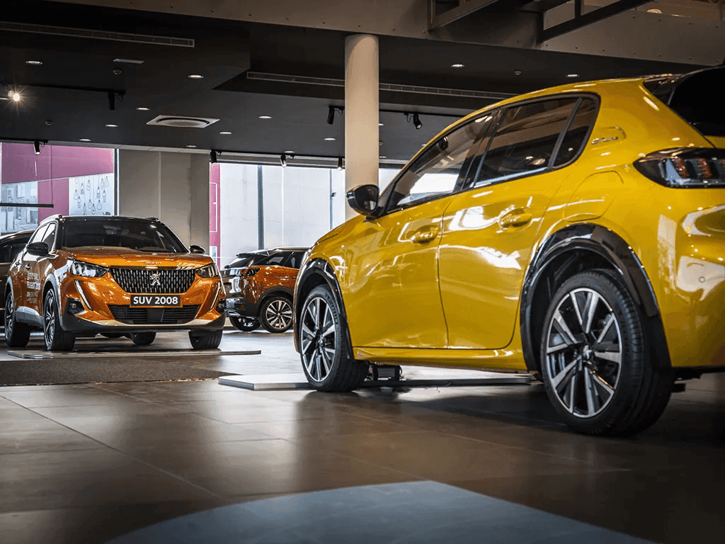 Imagen del interior del concesionario Peugeot con vehículos expuestos y zona de venta