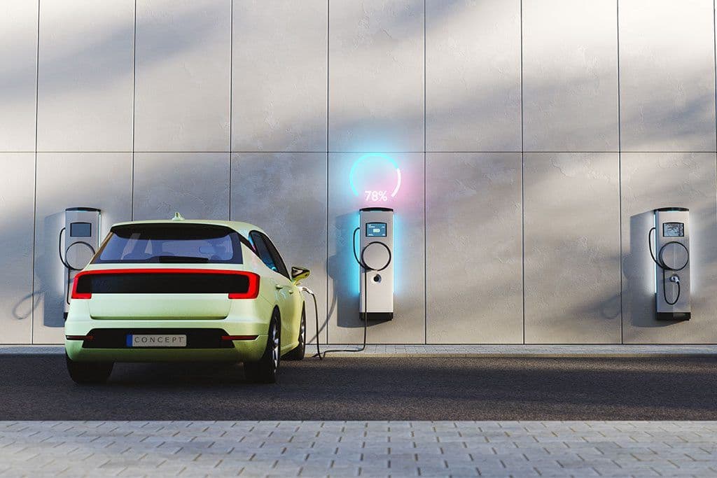 ¿Vale la pena dar el salto? Desmentimos los mitos sobre la autonomía y te explicamos cómo funciona la red de puntos de recarga actual. El futuro ya está aquí y es mucho más sencillo de lo que piensas. Coche electrico de color verde en zona de carga.